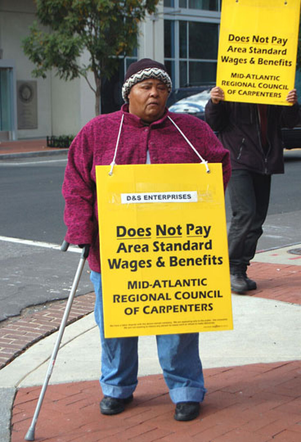 A woman pickets on behalf of the carpenter's union for $8 an hour.