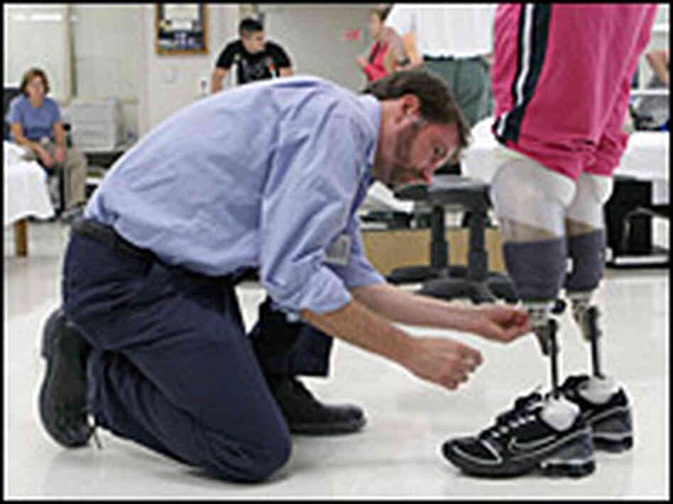 Prothetist David Beachler adjusts Downes' prosthetic legs.