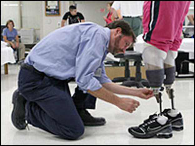 Prosthetist David Beachler adjusts Downes' prosthetic legs.