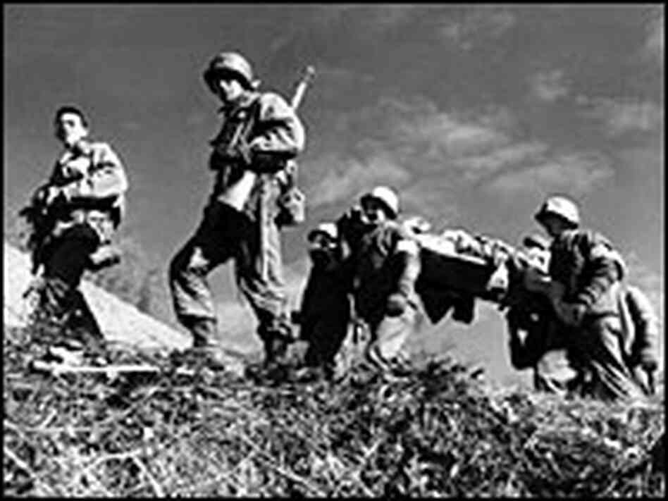 Soldiers carry a colleague who was wounded during attack Mount Belvedere