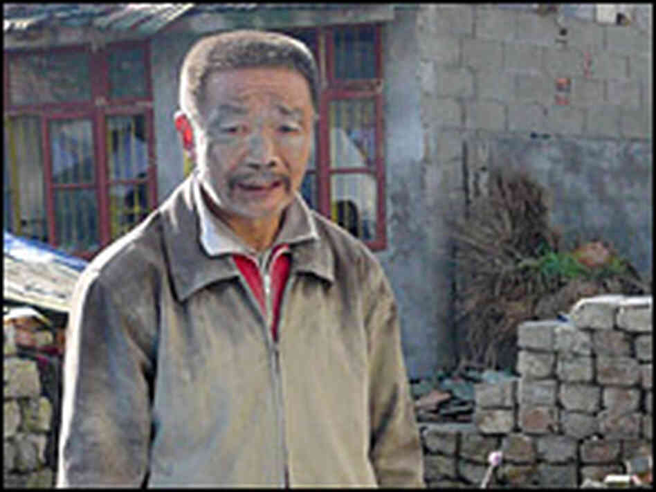 Xia Xueqi, 52, stands in front of the ruins of his house.