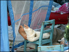 A patient's bandaged foot is elevated in a makeshift hospital. A patient's bandaged foot is elevated in a makeshift hospital.