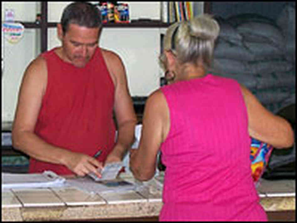 A worker at a state food distribution center in Havana records a woman's monthly food allotment.