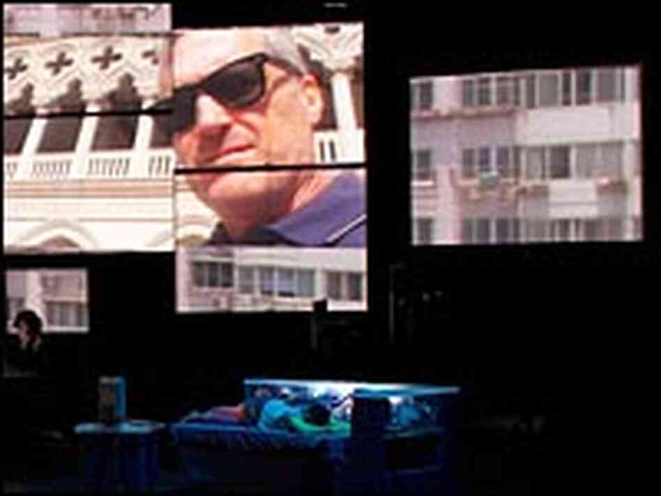Child in bed, faces on screens in a scene from 'Continuous City'