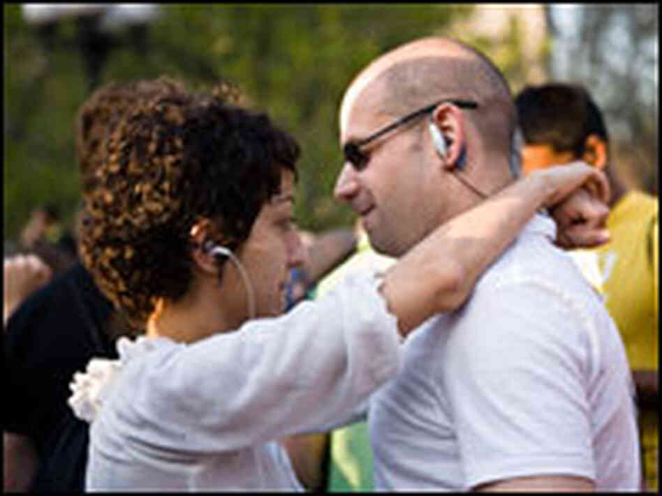 A couple wearing earbuds dances together at a silent rave.