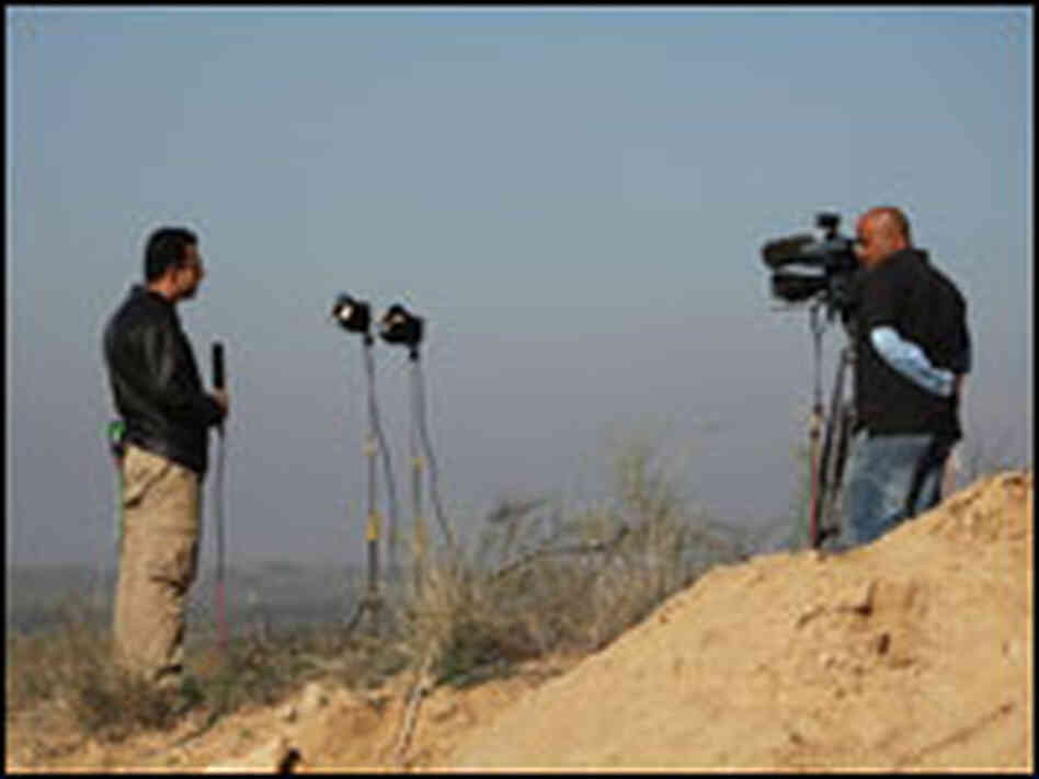 A cameraman and a reporter work on the Gaza border.
