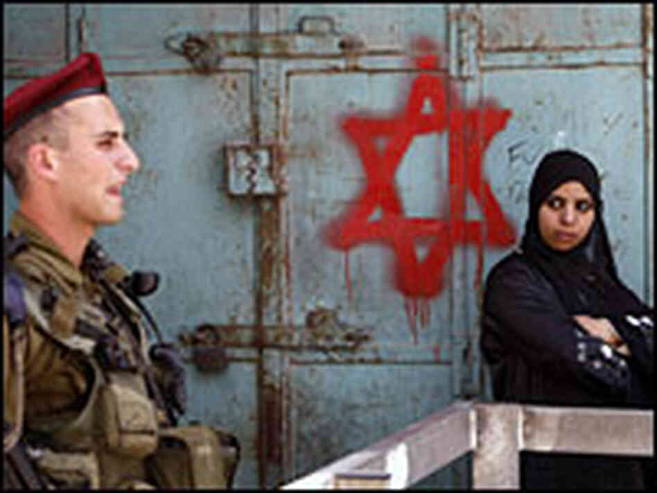 An Israeli soldier stands guard near a Palestinian woman in Hebron.