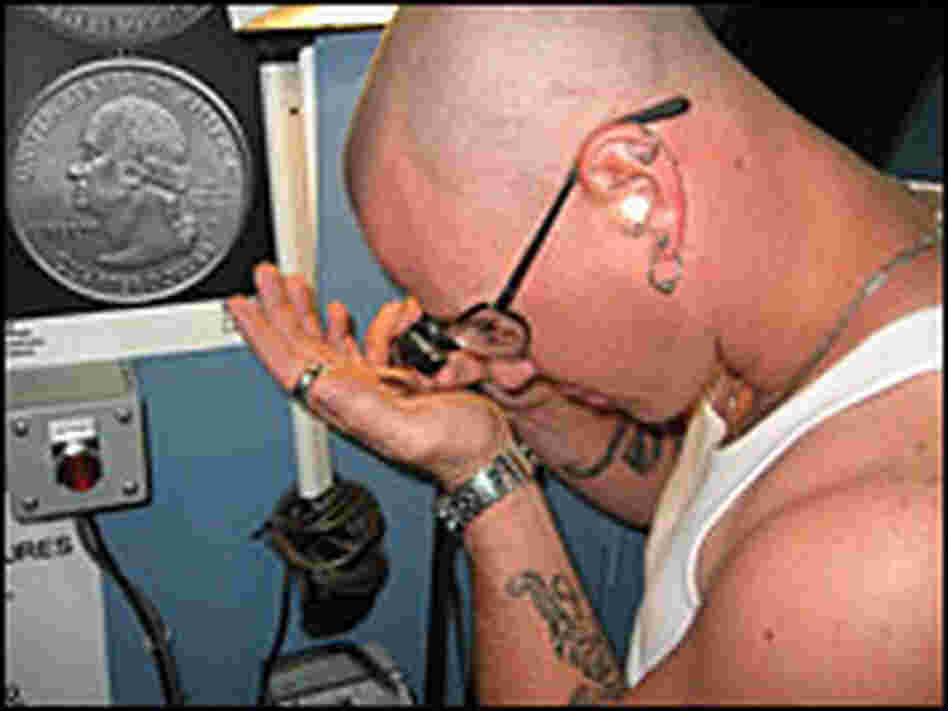 Denver Mint press operator Chris Wright closely inspects a Guam quarter.