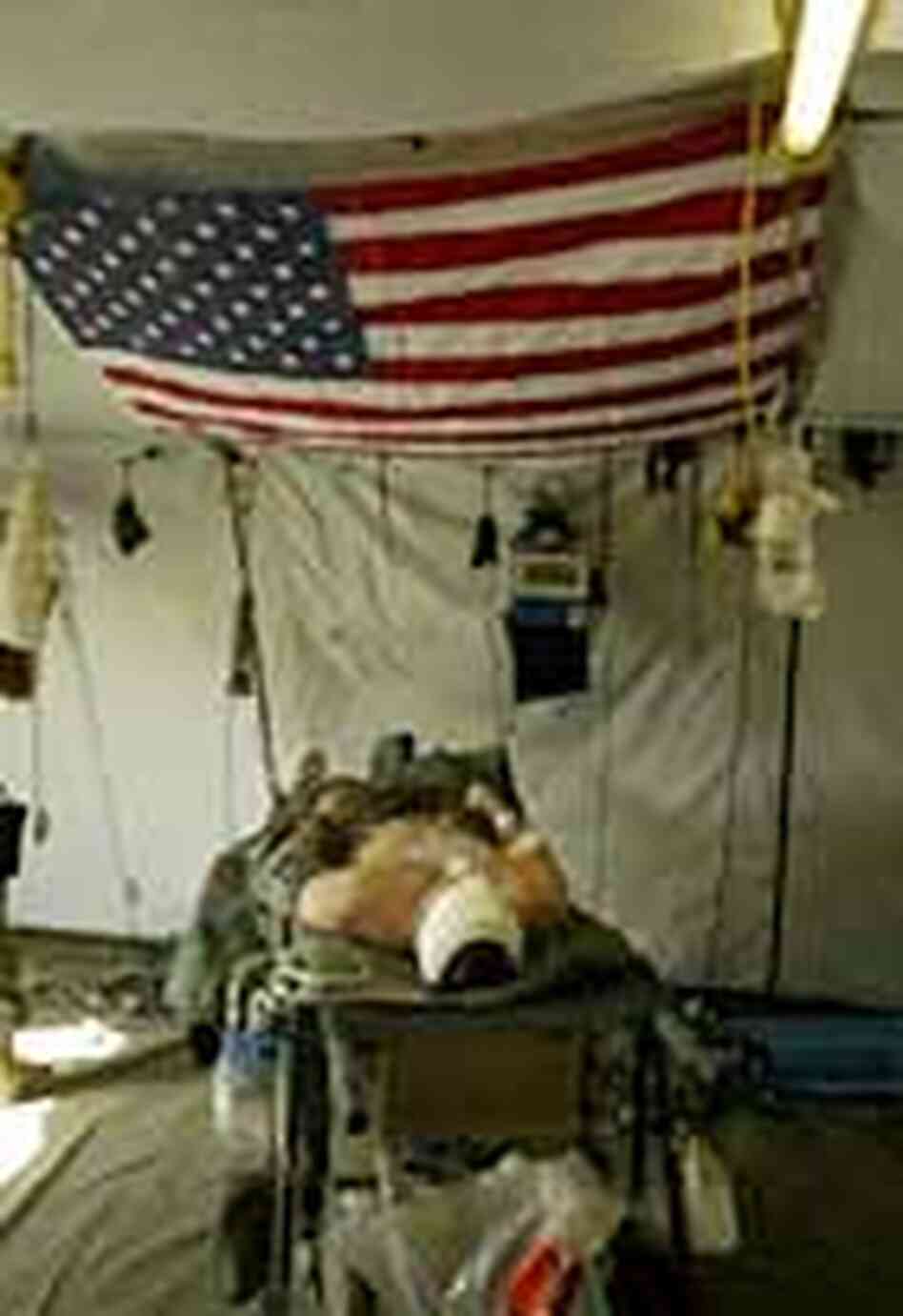 An injured U.S. Marine Corpsman lays under an American flag. An injured U.S. Marine Corpsman lays under an American flag.