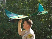 An L.A. County Sheriff's deputy hand-launches a pilotless drone surveillance aircraft.