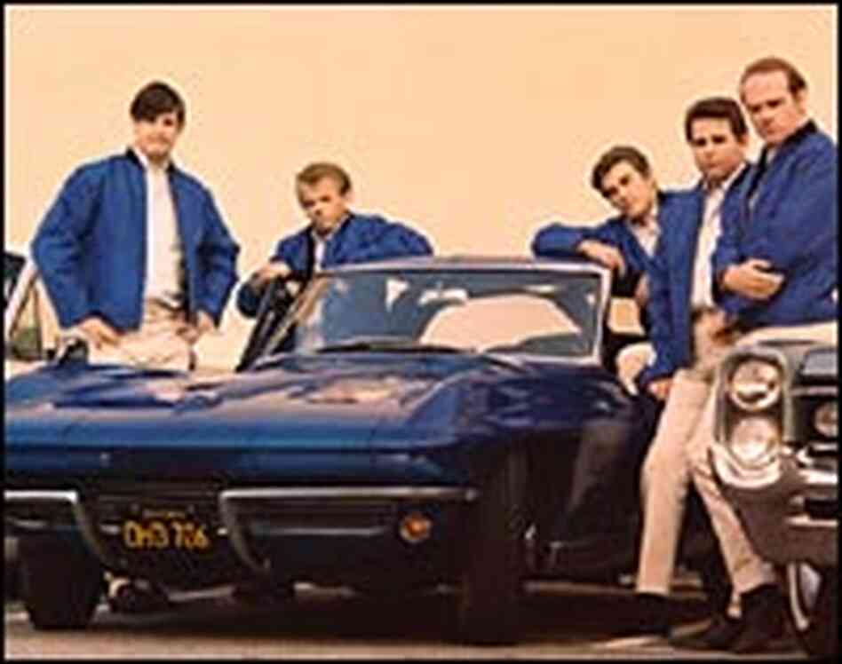 The Beach Boys pose with a classic example of an American muscle car. The Beach Boys pose with a classic example of an American muscle car.