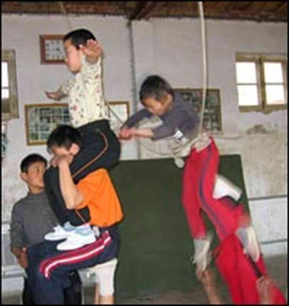 A group of boys practice a challenging 'pyramid' routine. The topmost boy wears a safety harness -- A group of boys practice a challenging 'pyramid' routine. The topmost boy wears a safety harness --