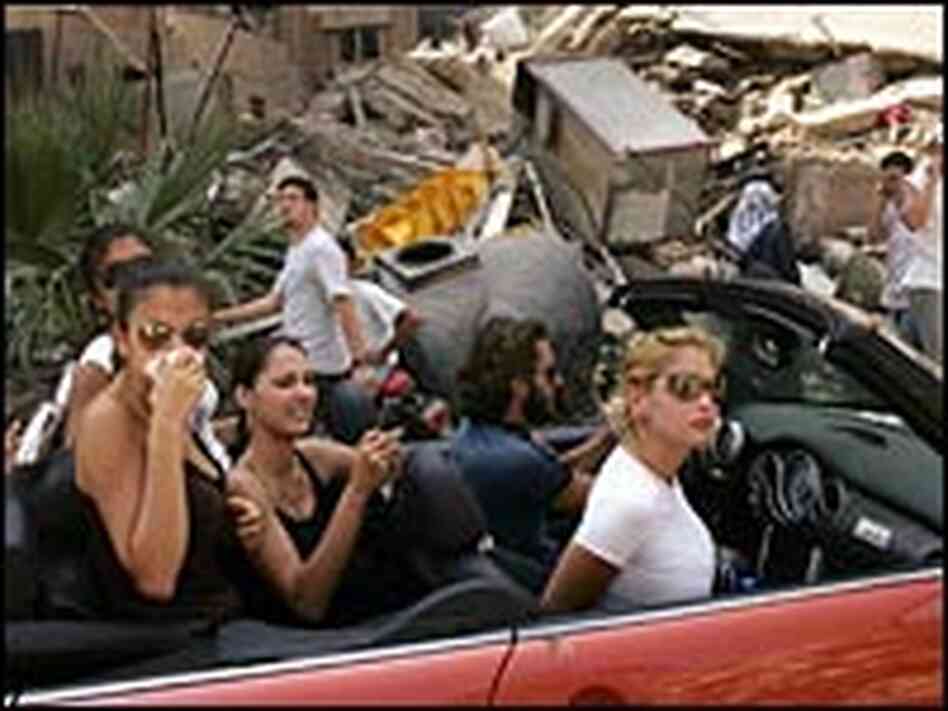 Affluent Lebanese drive down the street to look at a destroyed neighborhood