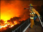 A firefighter surveys the flames. A firefighter surveys the flames.