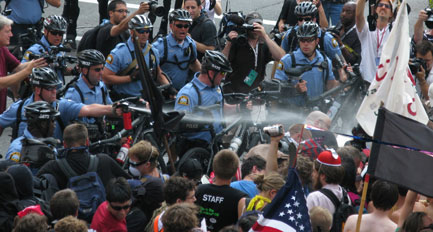 An officer releases spray on demonstrators.