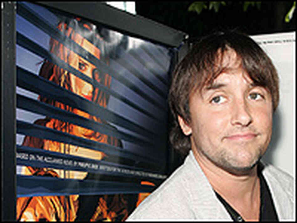 Richard Linklater, next to a poster of 'A Scanner Darkly'