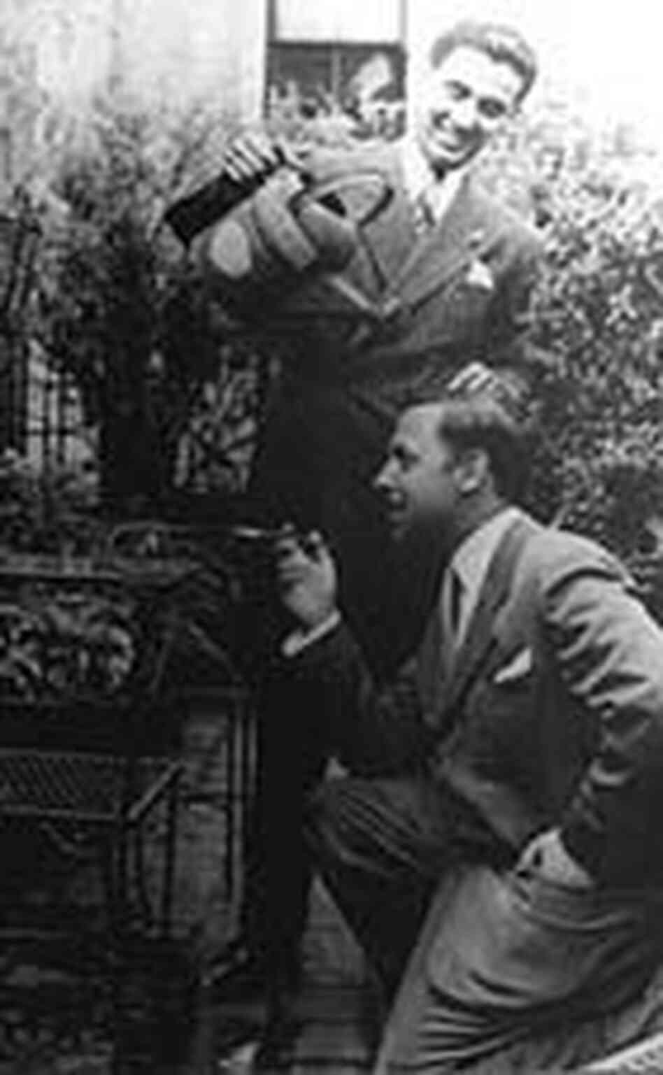 Tennessee Williams and Pancho Rodriquez in suits in a garden. One smokes. The other waters plants. Tennessee Williams and Pancho Rodriquez in suits in a garden. One smokes. The other waters plants.