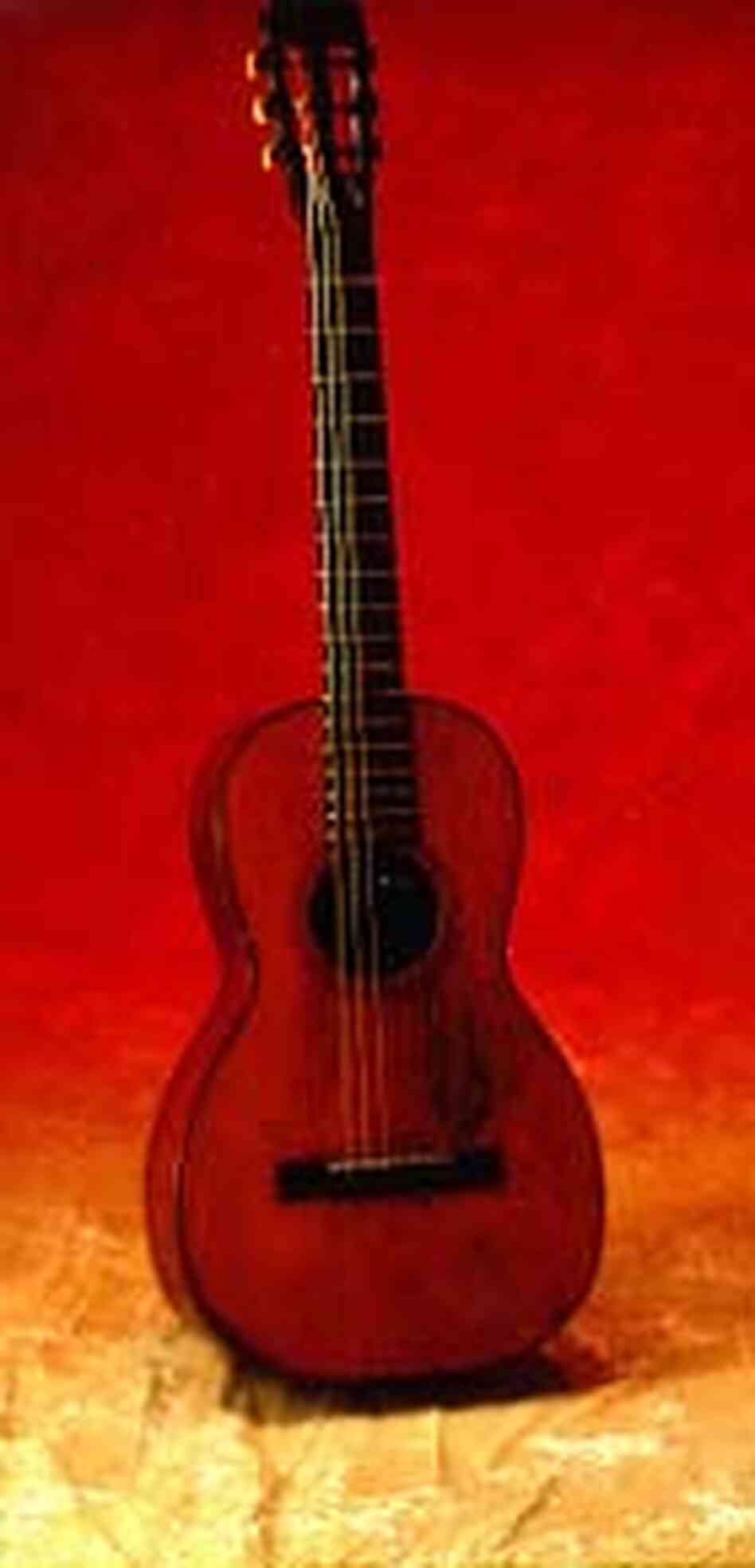 Mark Twain's guitar, a Martin, style 2½-17, stands upright. It is a rich, deep red color Mark Twain's guitar, a Martin, style 2½-17, stands upright. It is a rich, deep red color