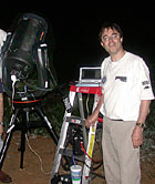 Andrew Chaikin stands next to his telescope.