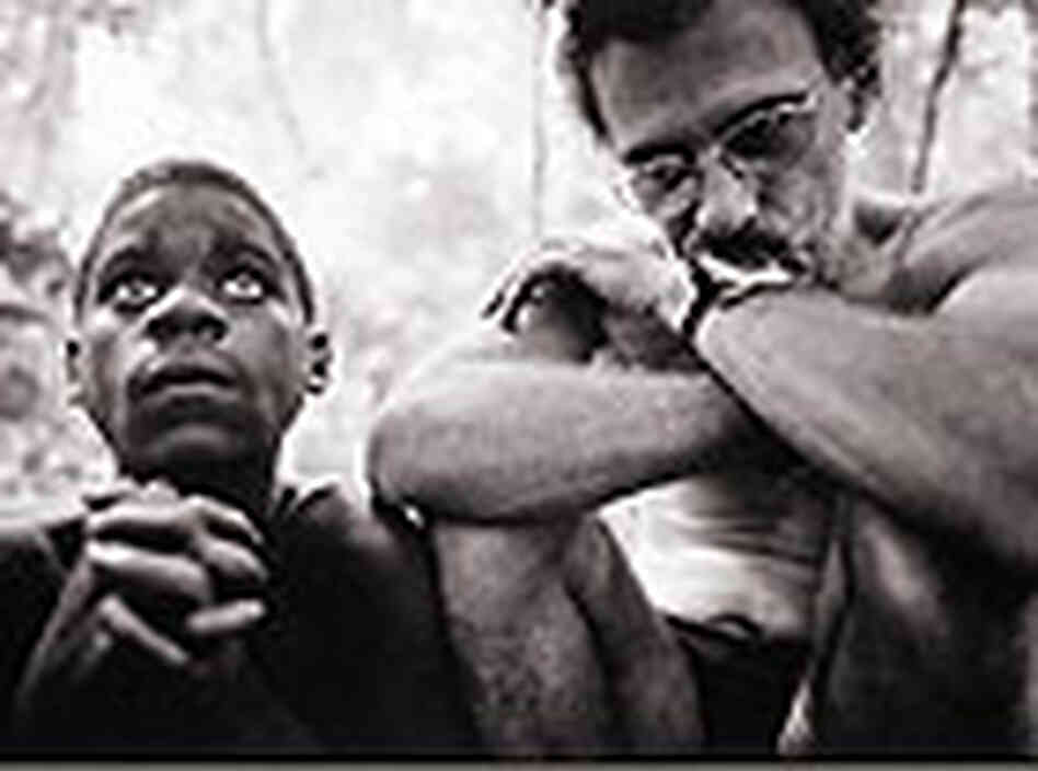 Michael Fay, right, sits before a morning campfire in Africa. Michael Fay, right, sits before a morning campfire in Africa.