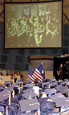 Soldiers in Baghdad are seen on a video screen at a Shoemaker High School graduation ceremony.