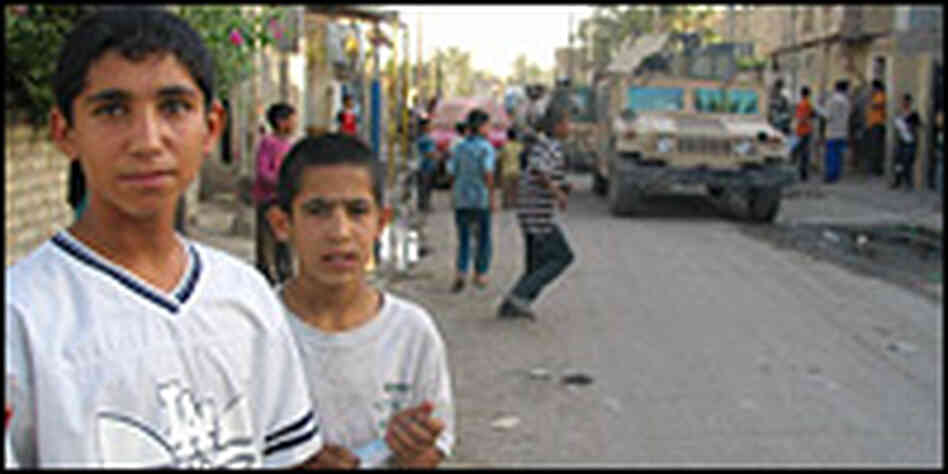 Two Iraqi boys stand in the street near to a patrol of U.S. Humvees in Sadr City. Two Iraqi boys stand in the street near to a patrol of U.S. Humvees in Sadr City.