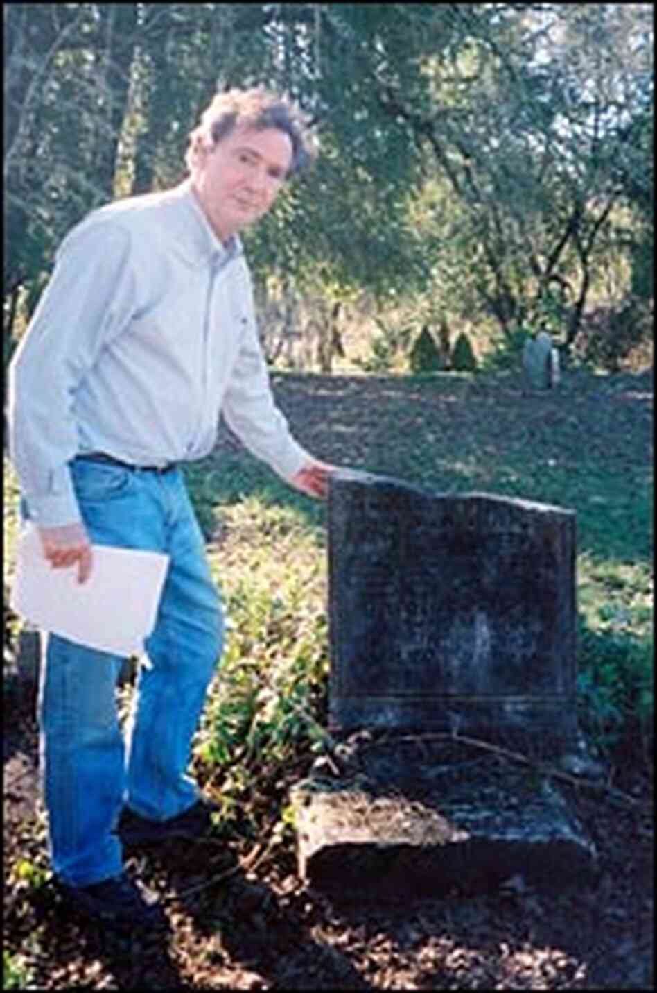 John Boatwright stands near broken headstone.