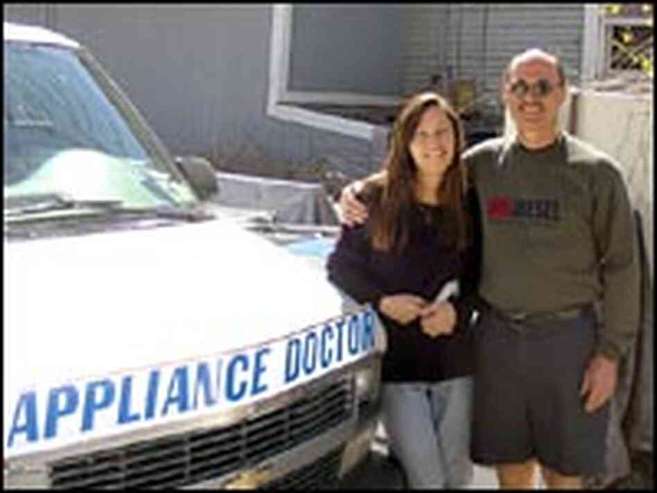 Mike and Dawn Ferrill stand next to appliance repair truck.