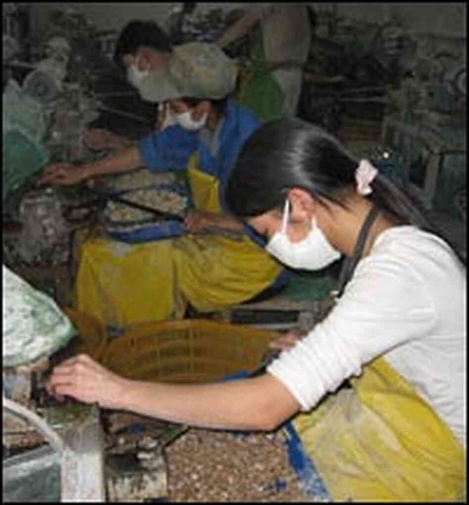 Workers buff baskets of buttons at a factory Workers buff baskets of buttons at a factory