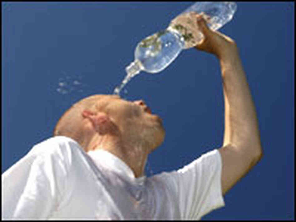 A runner pours a bottle of water over his head. A runner pours a bottle of water over his head.