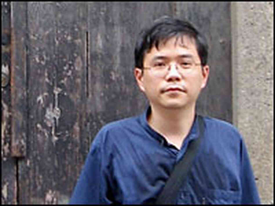 Shu stands outside the door of the house where he grew up.