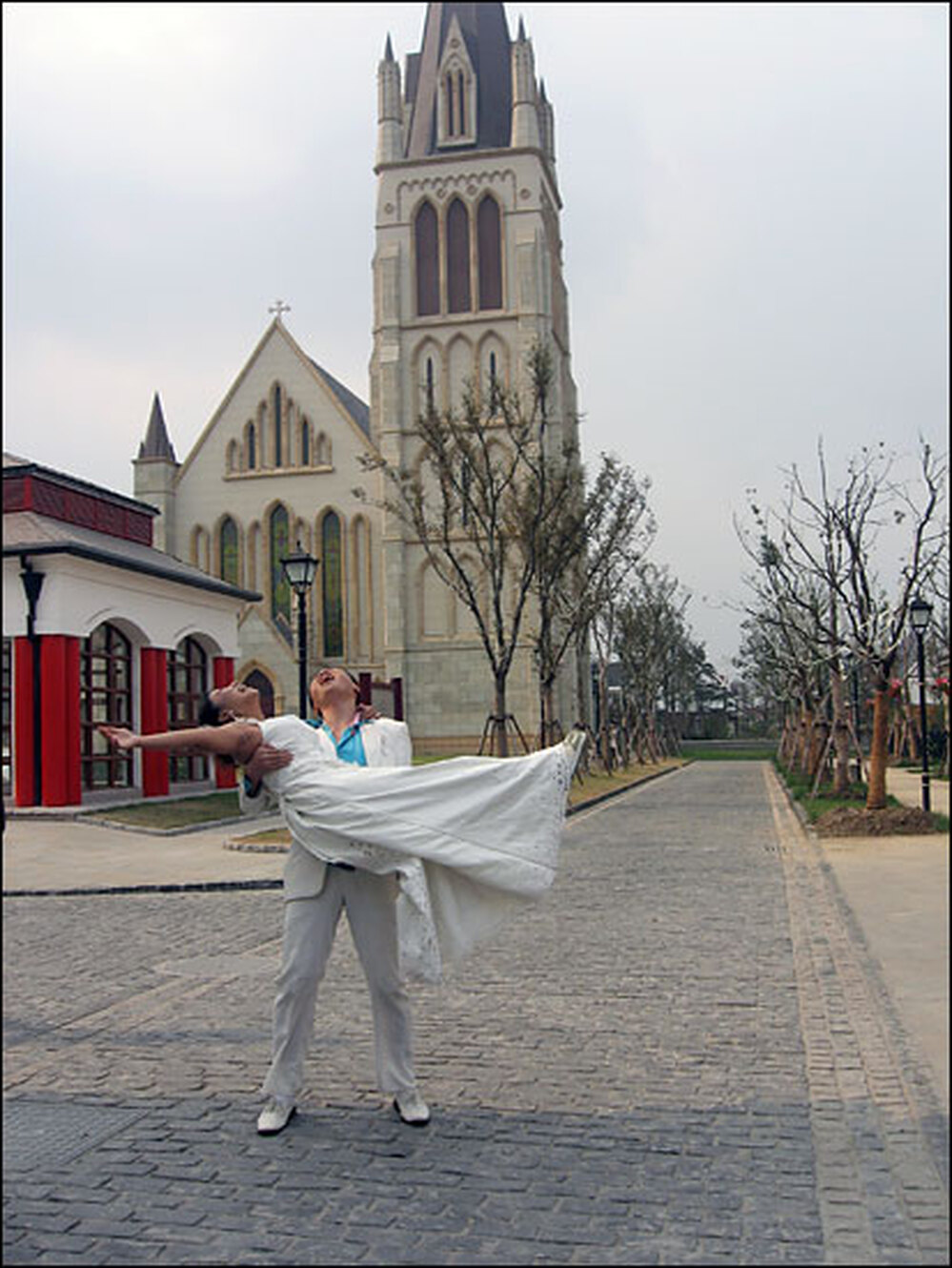Yang Jinghui and Zi Haiying pose for wedding photographs in front of Thames Town's church.