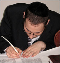A scribe writes the last letters in a Torah.