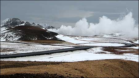 Steam from the Krafla power plant billows from behind a mountain.