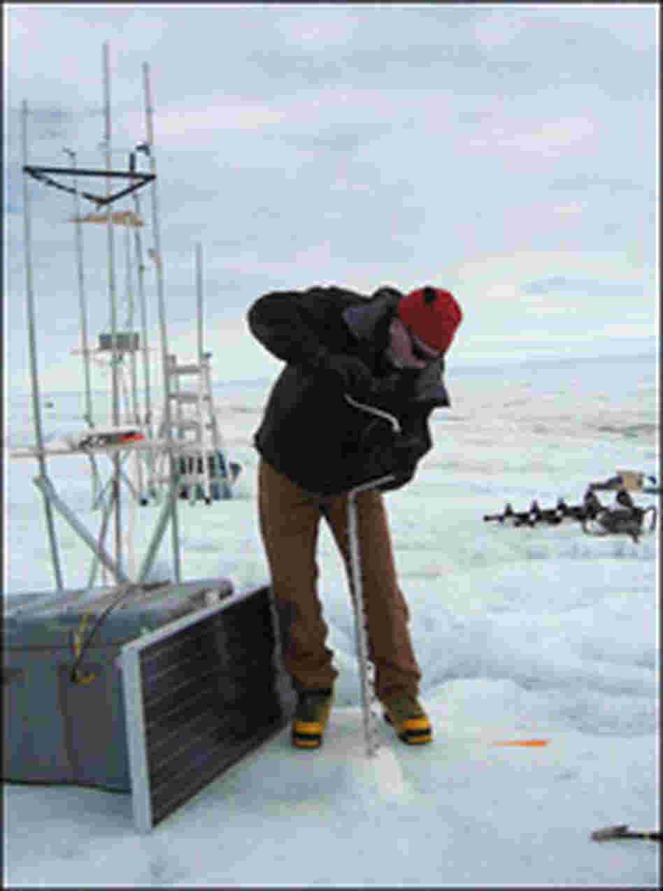 Ian Joughin uses an ice drill to sink a pole into the surface.