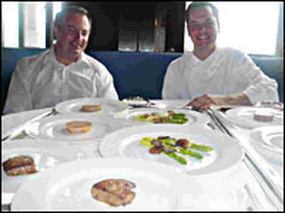 Chefs Eric Johnson and Stefan Stiller sitting at a table full of plates