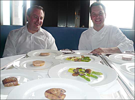 Chefs Eric Johnson and Stefan Stiller sitting at a table full of plates