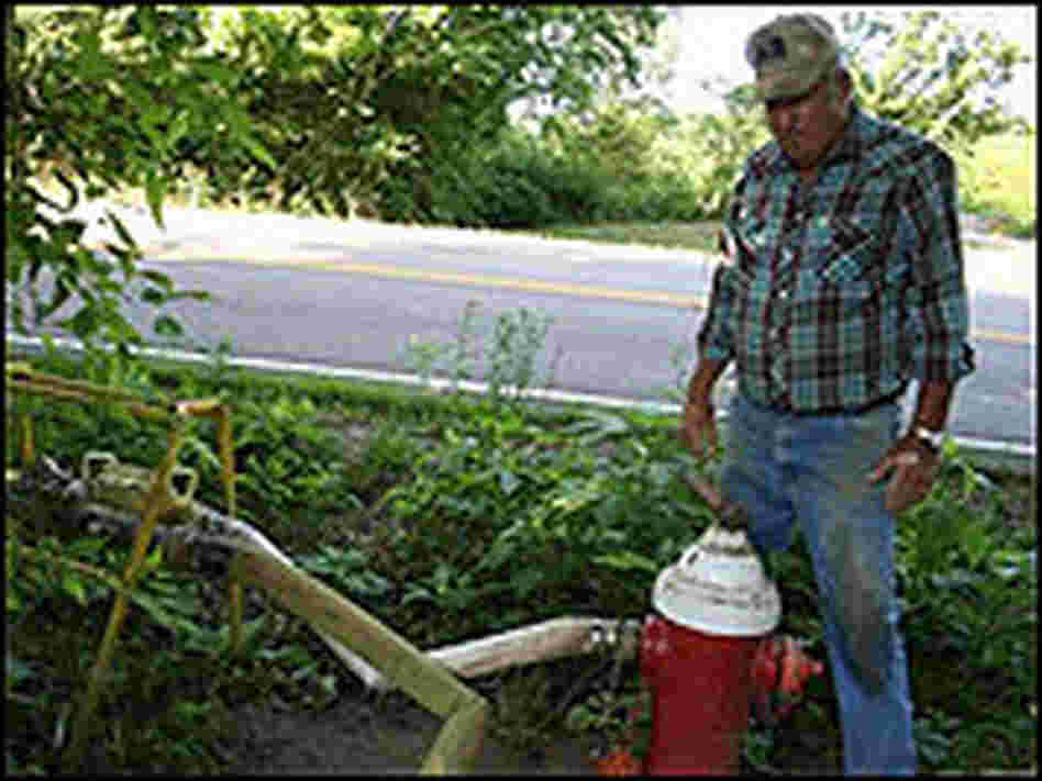 A farmer transfers water from a fire hydrant to the crops.