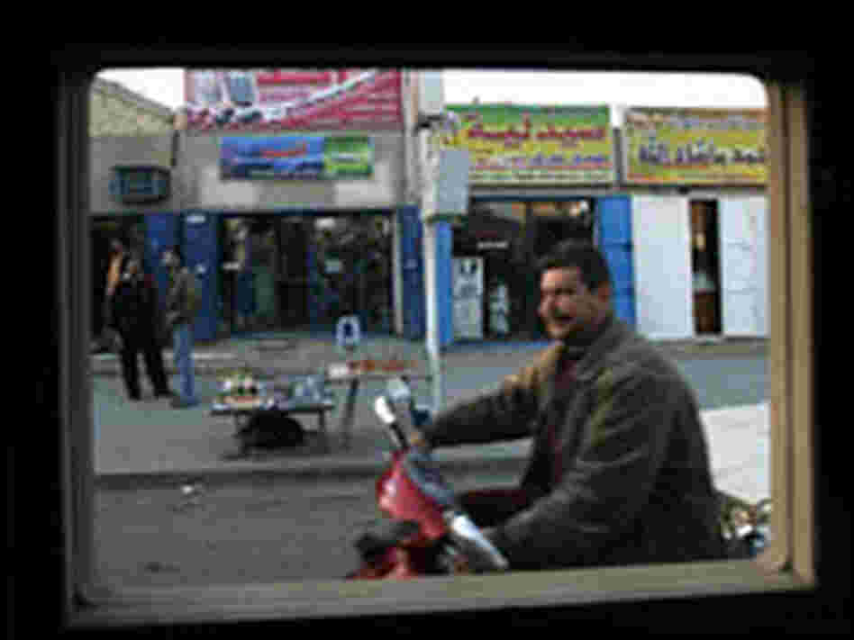 A man rides a scooter, as seen through a U.S. military Humvee window, in Baghdad.