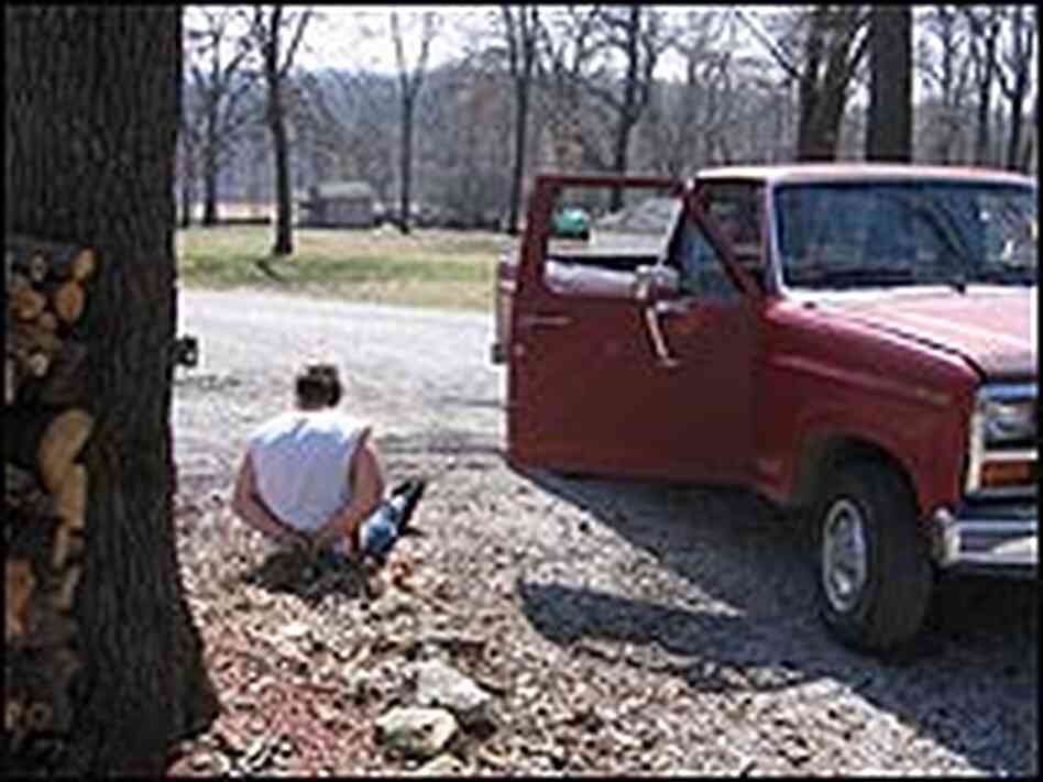 A handcuffed man sitting next to a red pick-up truck, arrested for meth and parole violations. A handcuffed man sitting next to a red pick-up truck, arrested for meth and parole violations.