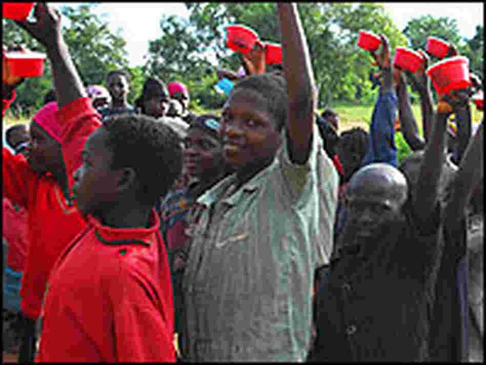 Children hold up cups used to collect stool samples.