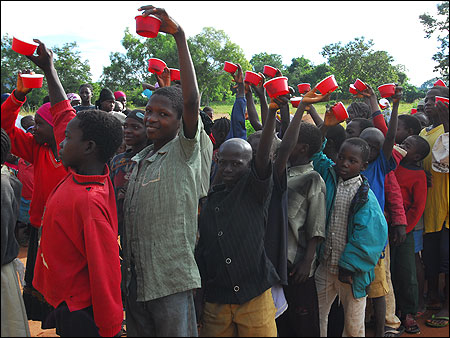 Children hold up cups used to collect stool samples.