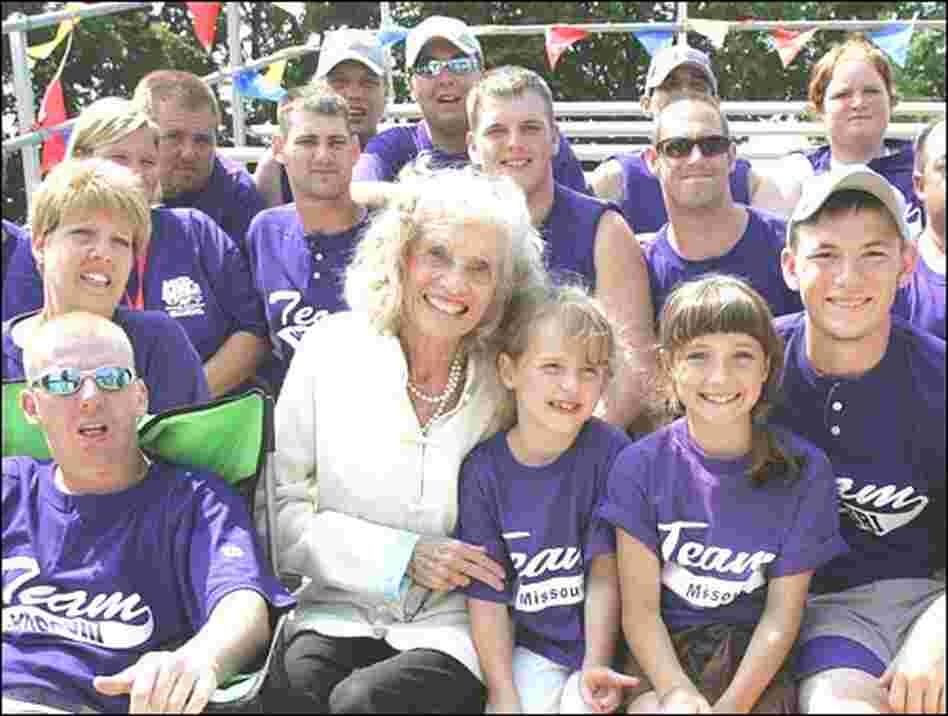 Shriver sits surrounded by more than a dozen members of a Special Olympics baseball team.