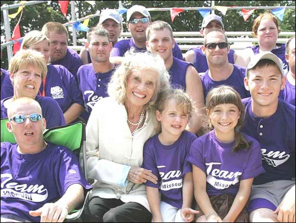 Shriver sits surrounded by more than a dozen members of a Special Olympics baseball team.