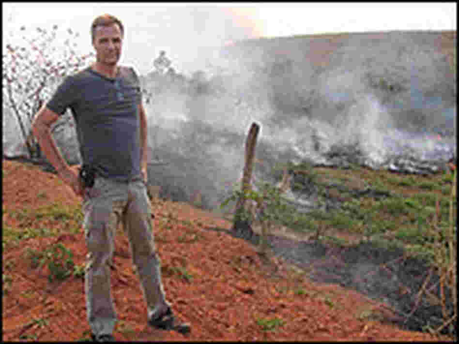 Dan Nepstad, a Woods Hole researcher, stands before a patch of smoldering Amazon forest.