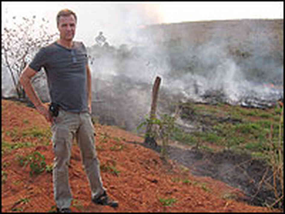 Dan Nepstad, a Woods Hole researcher, stands before a patch of smoldering Amazon forest.
