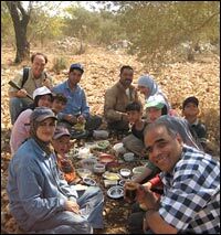 Fareed Taamallah (back left, next to Sandy Tolan), his sister-in-law, Umm Imad (foreground, with baseball cap), family and friends, pausing for lunch under the olive trees in the West Bank village of Qira.
