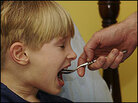 A boy opens his mouth for a spoonful of medicine. A boy opens his mouth for a spoonful of medicine.