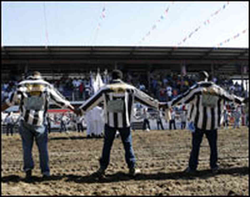 Inmates dressed in striped convict shirts form a prayer circle at the start of the rodeo.