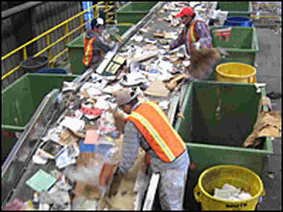 Workers sort through recycled paper and cardboard on a conveyor belt at Willimantic Waste Paper Co.